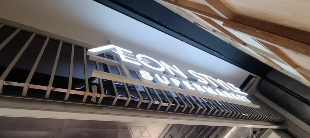 AEON: Illuminated AEON Style Supermarket entrance lettering from below — actual site photograph